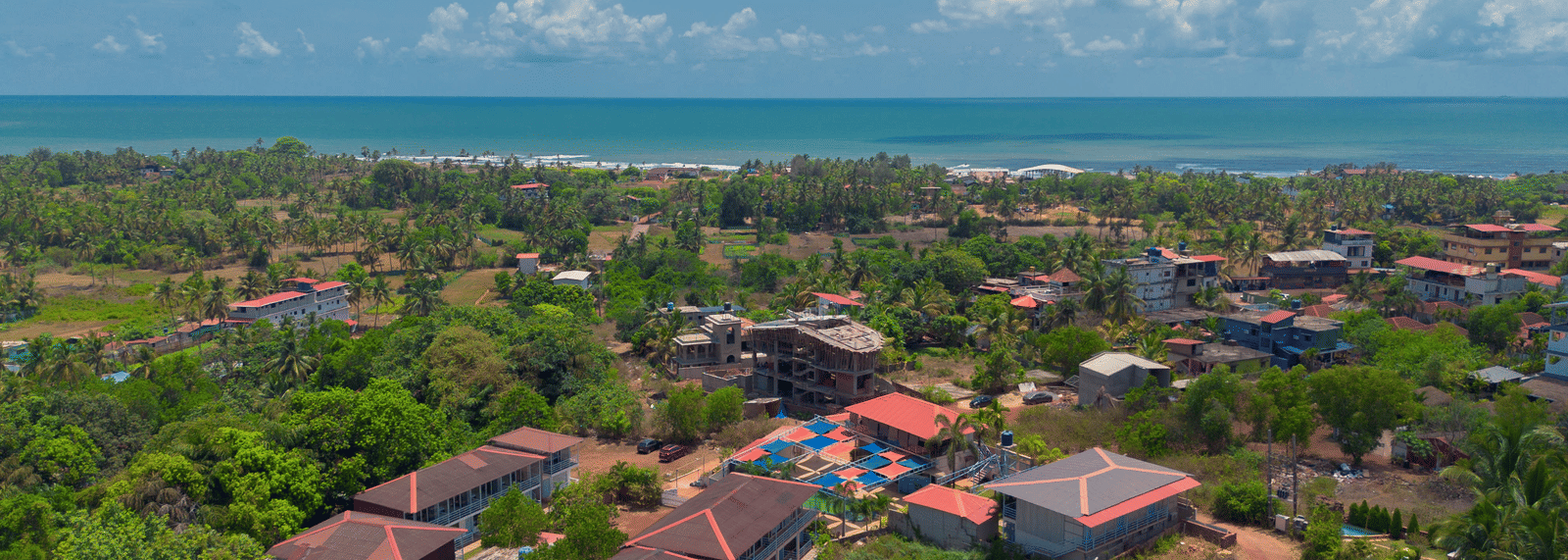 An aerial view of our resort, surrounded by lush green trees with Morjim Beach visible at the edge - Perfectstayz Koko Maya