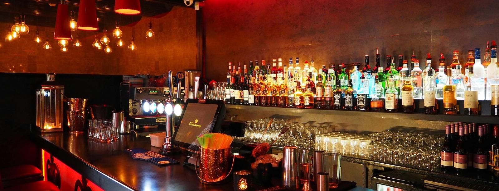 Assorted bottles of spirits inside a bar with warm lighting.