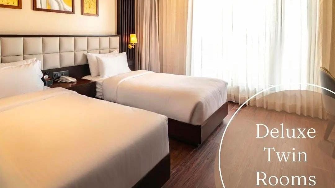 A image of a room with twin beds and lights seeping into the room from a window