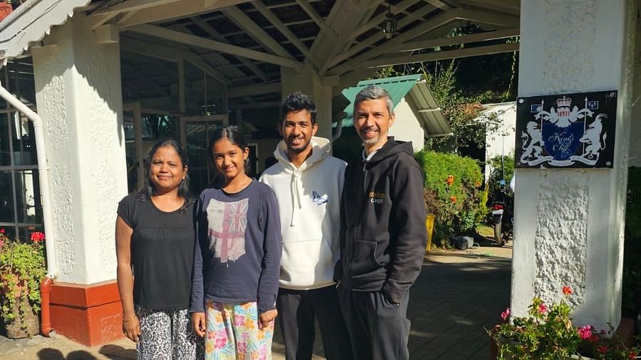 Group of guests posing at the entrance of a white cottage-style resort building.