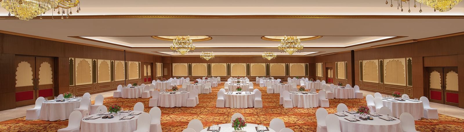 A banquet hall in Mahabalipuram with chandeliers, carpeted floors, and a cluster-type seating arrangement – Kaldan Samudra Palace, a Beautiful Wedding Venue ECR