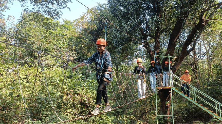 Adventure enthusiast crossing a zipline course amidst lush forest landscapes.