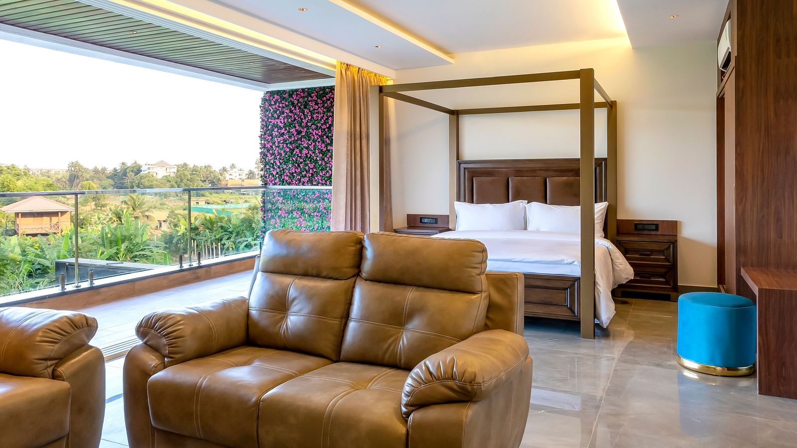 A double bed with wooden beams with a sofa in front of it inside one of the rooms - The Tanisi Hotels & Resorts, Goa