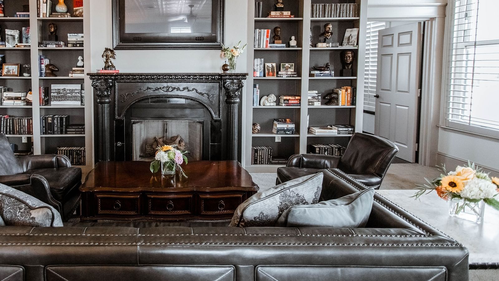  A stylish living room with large bookshelves, a fireplace, and plush seating, creating a warm and inviting atmosphere - The Grand Hotel & Ballroom, McKinney