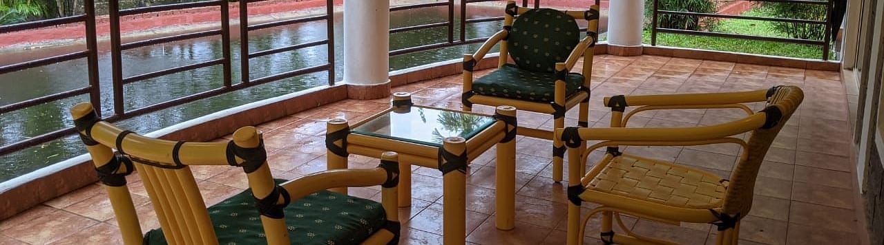 Outdoor seating area on a covered balcony with a scenic forest view at The Conservancy Bungalow.