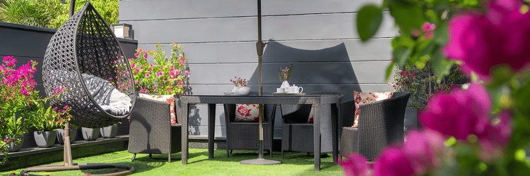 An inviting outdoor patio at The Atara, Gurugram featuring a dining set with an umbrella for shade, surrounded by vibrant blooming flowers and lush green foliage, perfect for relaxation