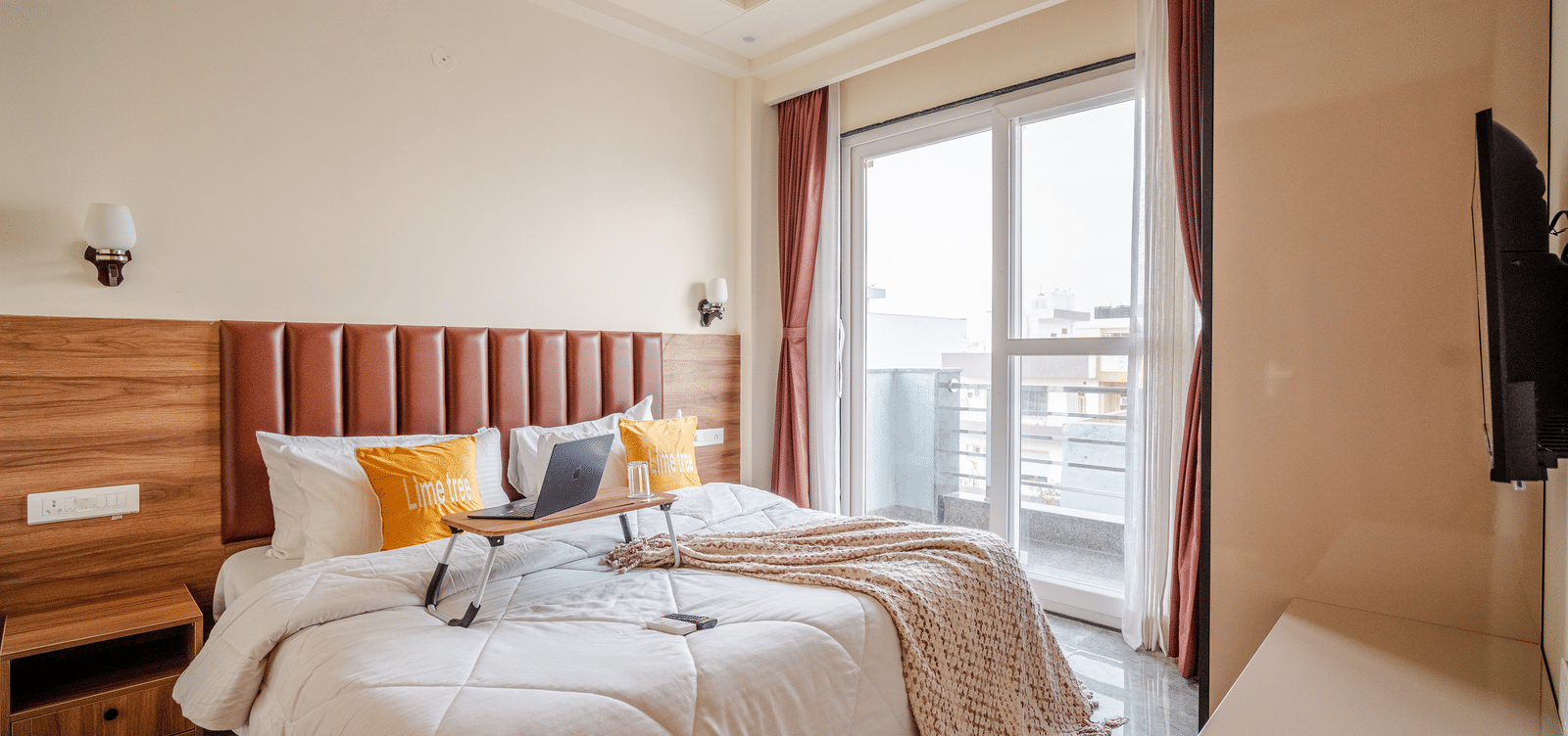 Comfortable bedroom with a large bed, soft furnishings, and a window view at Lime Tree 1BHK Service Apartment Near Artemis Hospital Gurgaon.