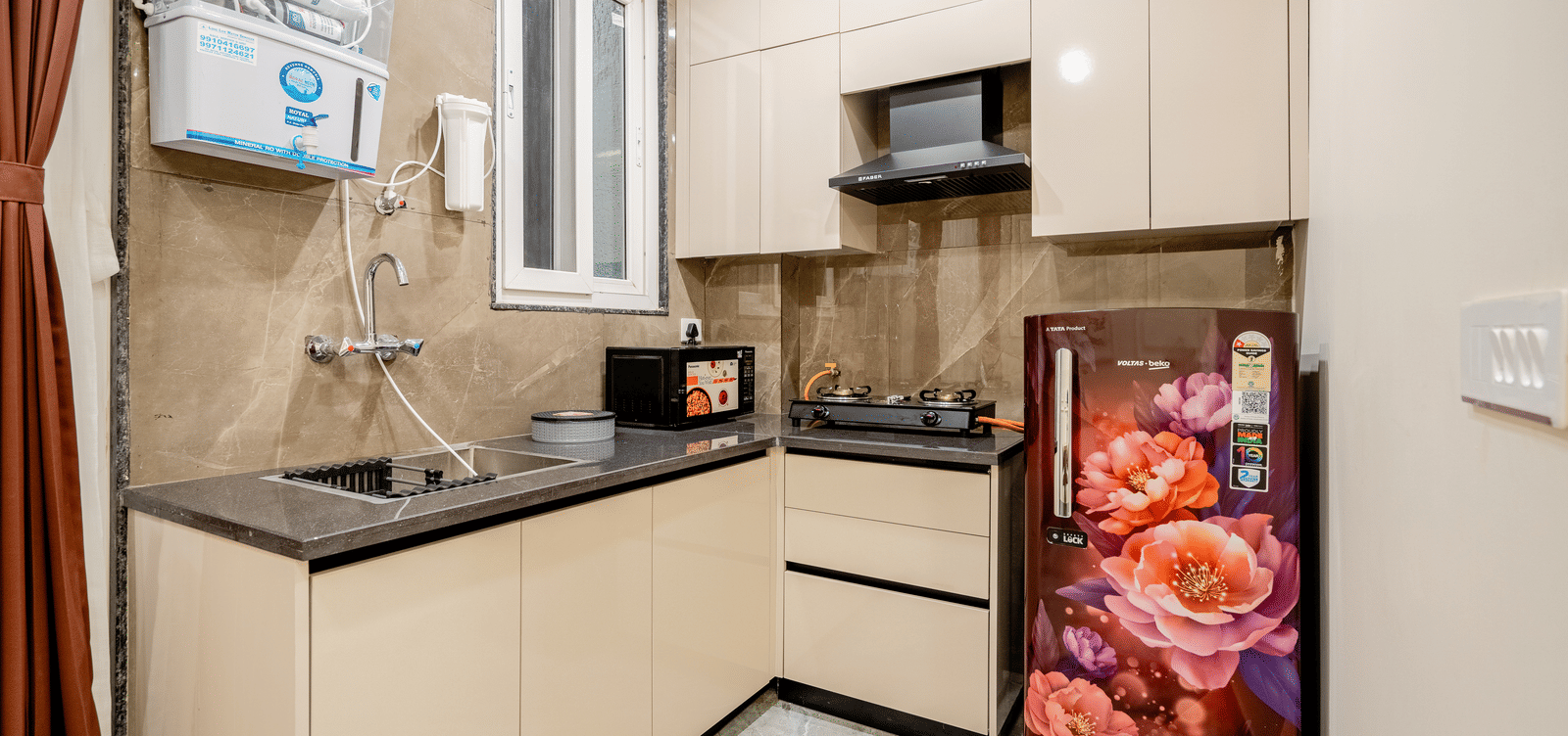 Modern kitchen with cabinets, sink, and refrigerator at Lime Tree 1BHK Service Apartment Near Artemis Hospital Gurgaon.