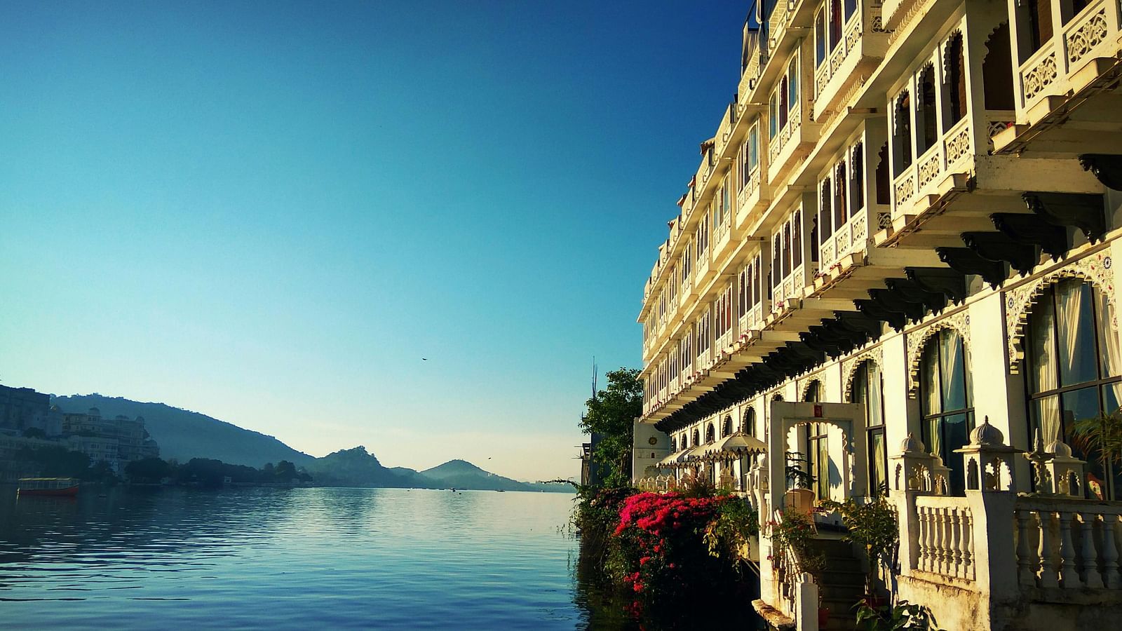 A lake view with mountains in the background and a building occupying half the frame in the foreground