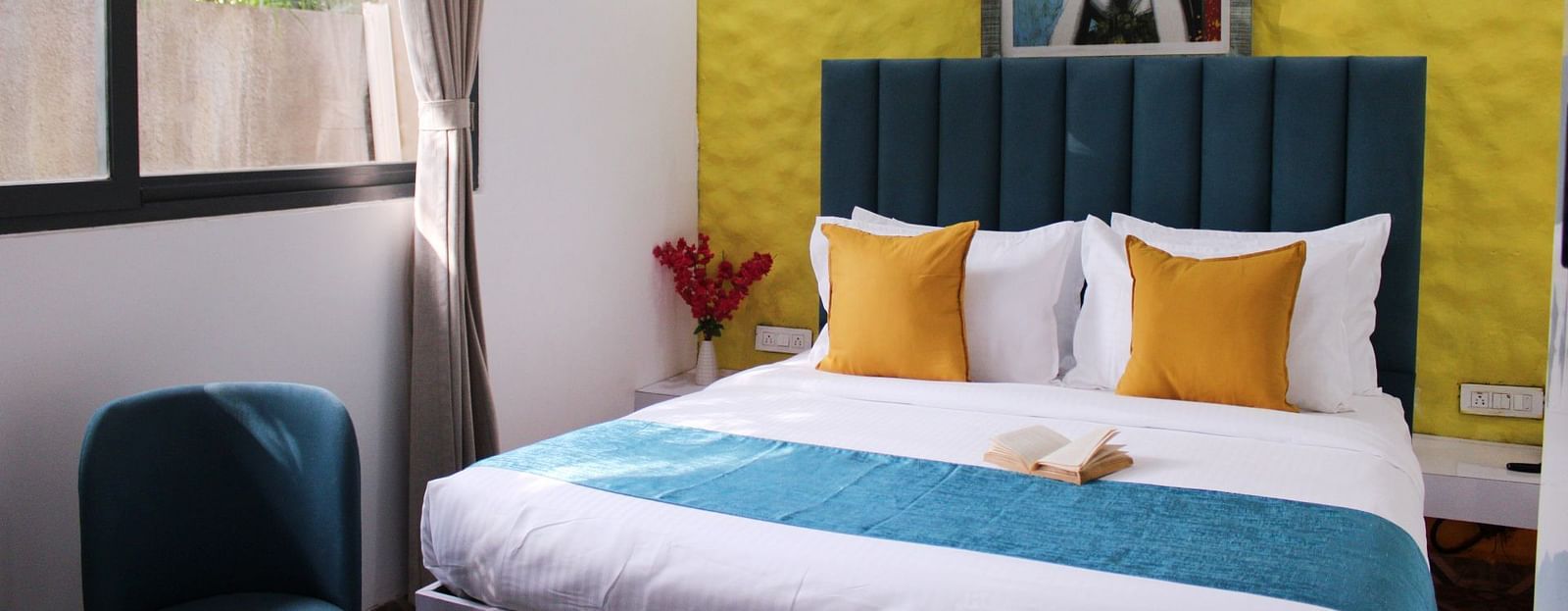 A king size bed with a painting in the background of a Deluxe Cottage Room at Royale Amata - By the Beach.