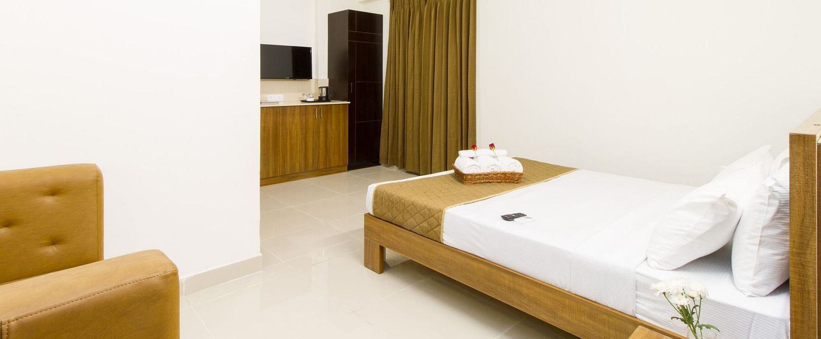 A furnished hotel room featuring a double bed and an armchair at Sanctum Suites Whitefield, Bangalore.