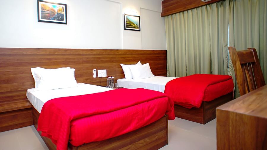 Deluxe With Breakfast room featuring twin beds, a wooden work desk with chair, AC at Mastiff Hotel, Chinchwad, Pune.