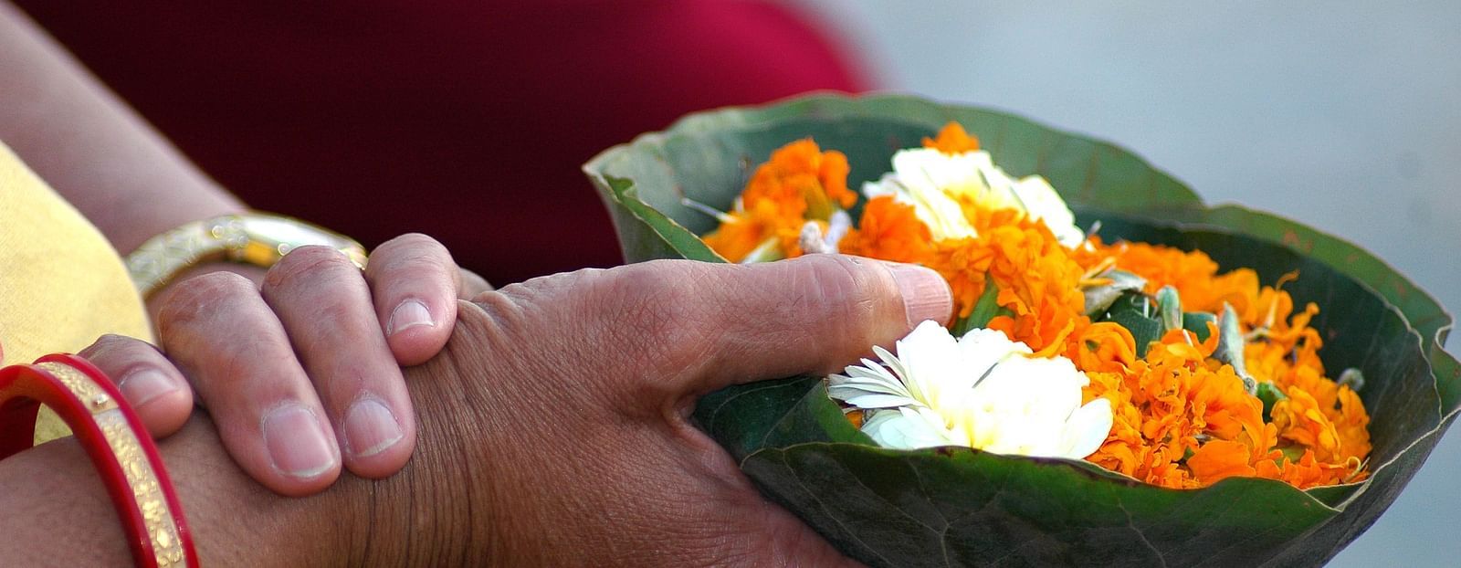 Hands offering flowers to the Ganges River as a religious ritual.