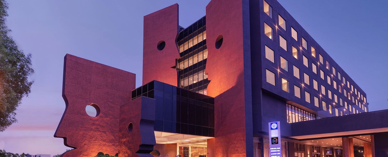 Far out view of Essentia Luxury Hotel, Indore during blue hour with the lights on.