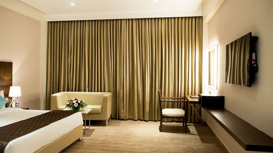 Entrance of the Premium Room with a large bed facing the television at Grand Ashok, Thanjaviur.