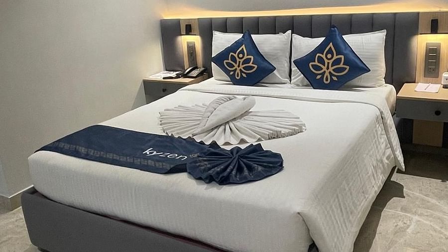 Brightly lit bedroom with a plush bed and decorative pillows at Hotel Kyzen HiTech City – Your Zenly Stay