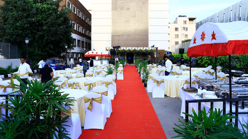 A spacious outdoor dining setup with white and gold chairs and a red carpet leading to the main venue - Grand Continent, Brookefield