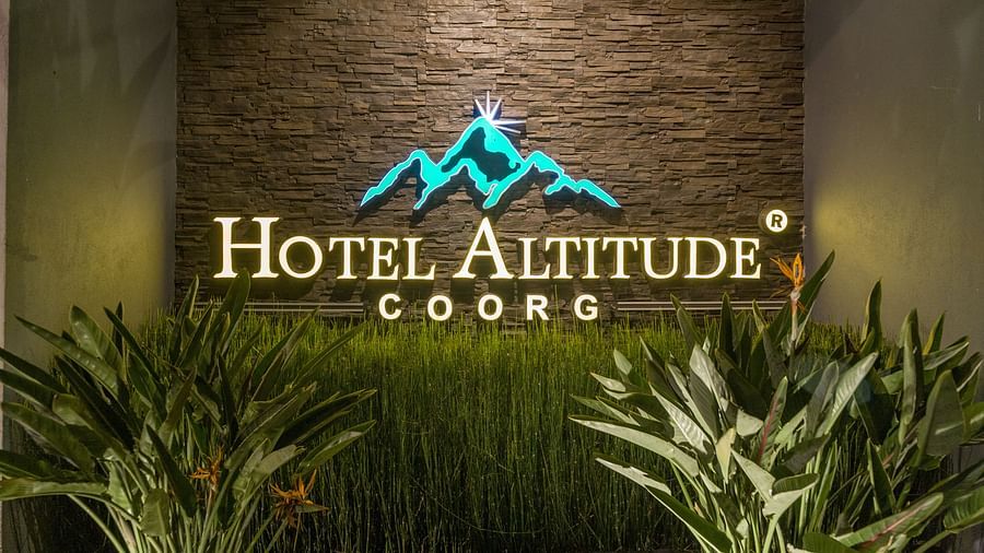 Image of a wall with Hotel Altitude written on it and with plants in front at Hotel Altitude, Madikeri.