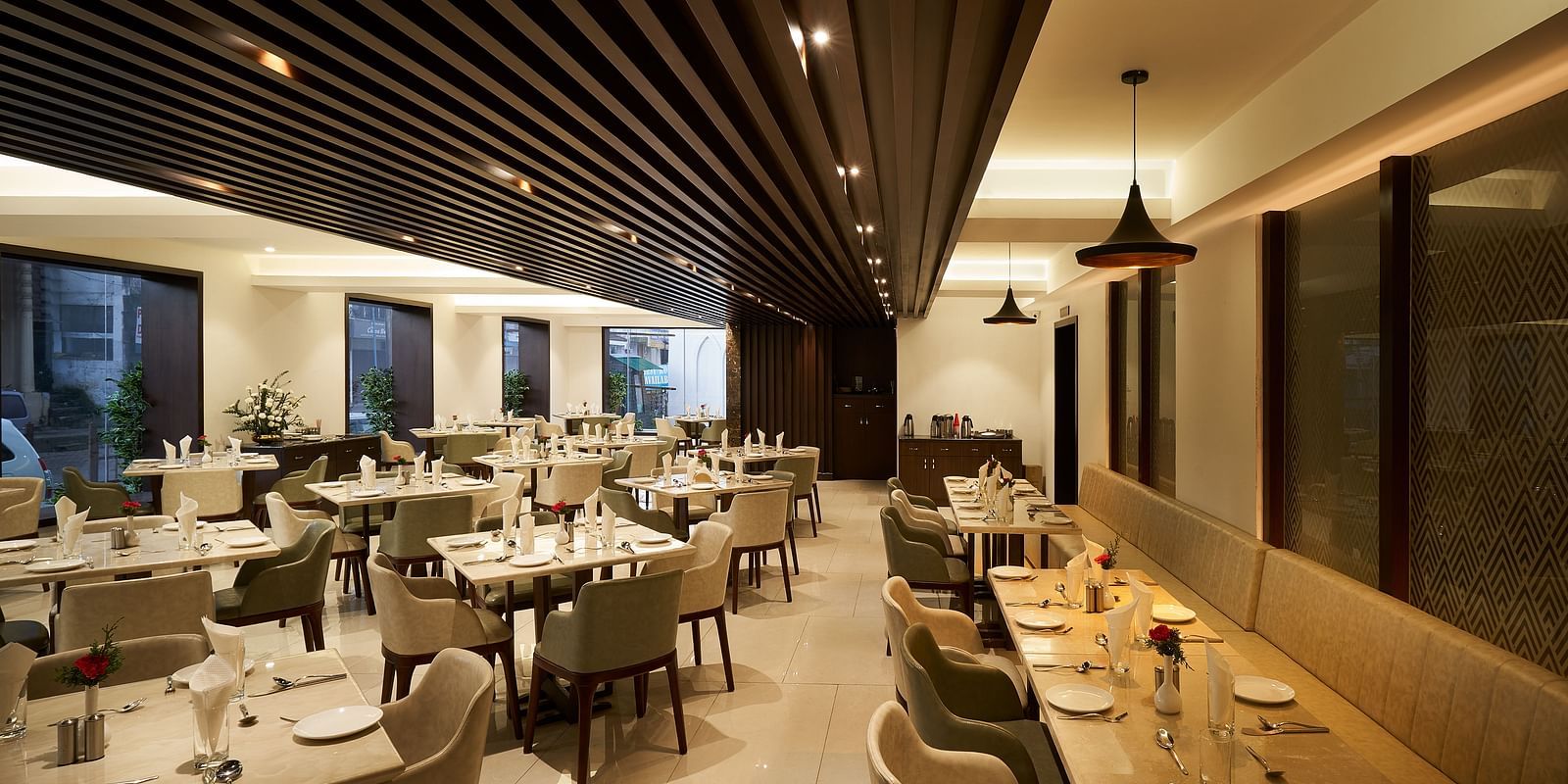 Spacious dining area with tables and chairs on one side, and seats along the wall on the other at The Hamuse Hotel, Kodaikanal.