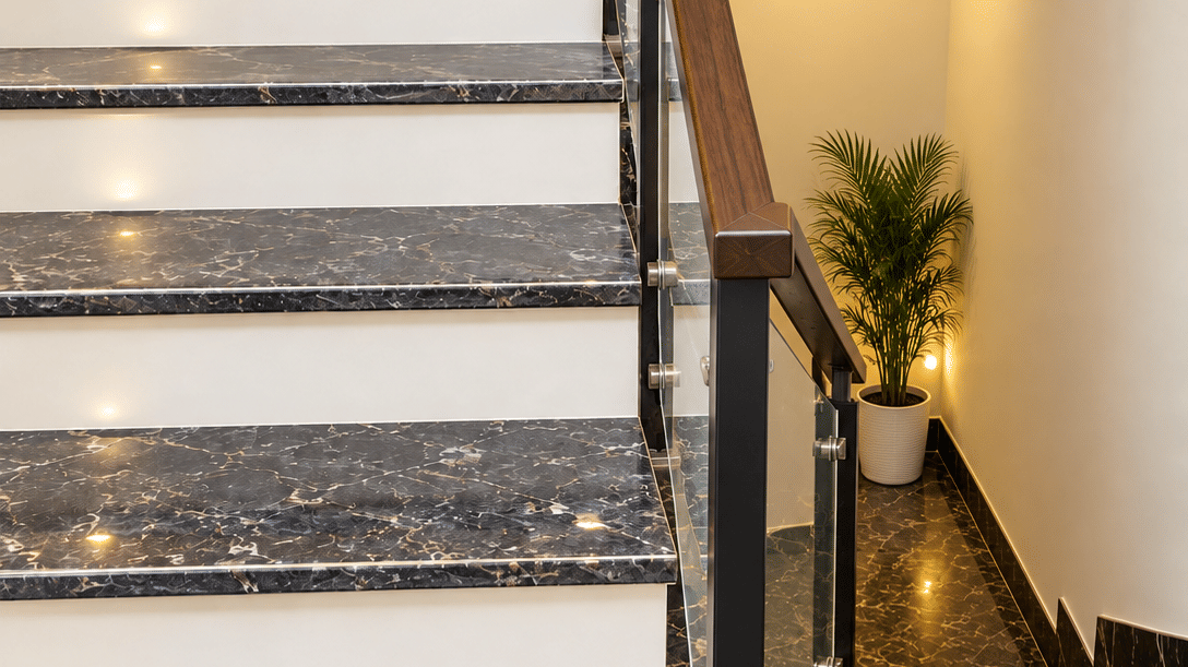 Marble staircase with a glass railing and a potted plant.