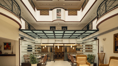 Pavilion at The Residency Karur features a patterned floor, seating areas, and glass-enclosed spaces under a skylight.