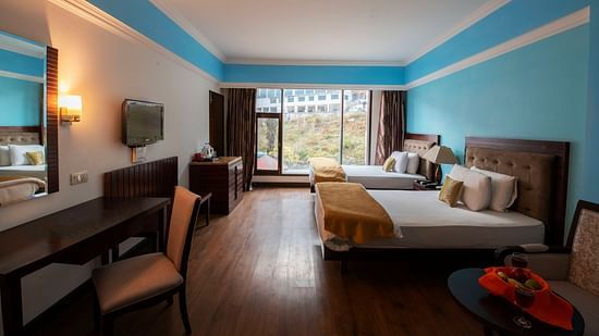 A spacious room with twin beds, a TV, desks, chairs, mirror and a big balcony - Mastiff Grand, Manali