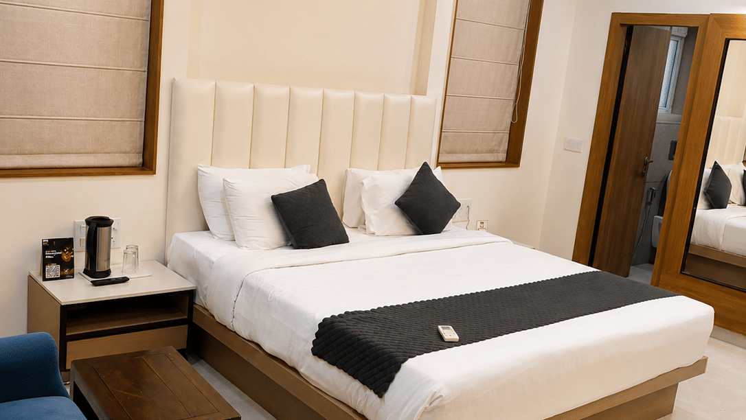 Suite at TGI Apple Inn, Ajmer Road, Jaipur featuring a bed, bedside tables, armchairs, blinds on the windows, and a door.