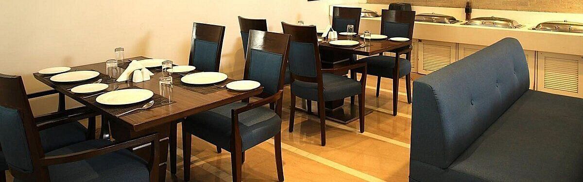 Tables and chairs neatly arranged with cutlery set on the table at Café Inde, Inde Signature Tower, Gurgaon