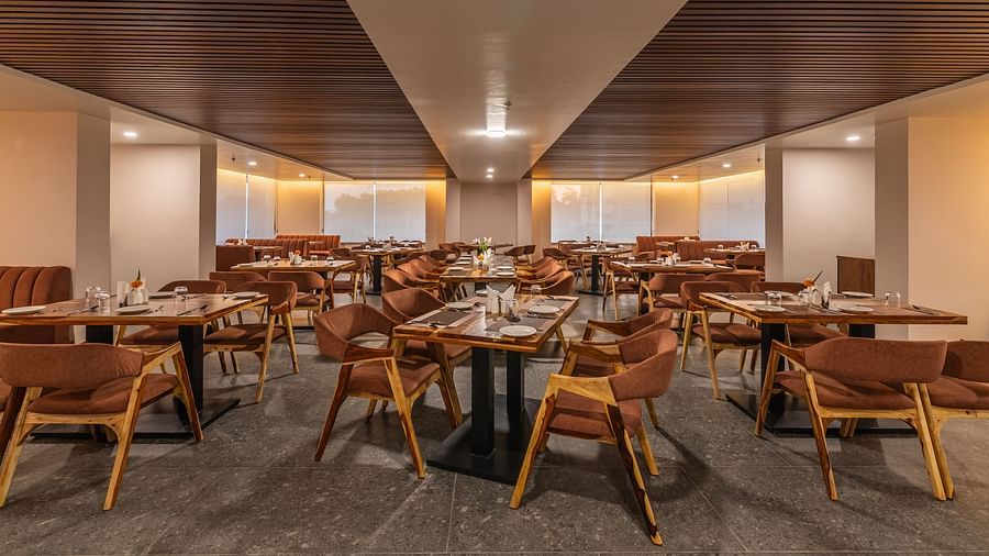 Dining area with wooden chairs, elegant tables, and warm lighting at Clarks Inn Suites Jaipur, Ajmer Road
