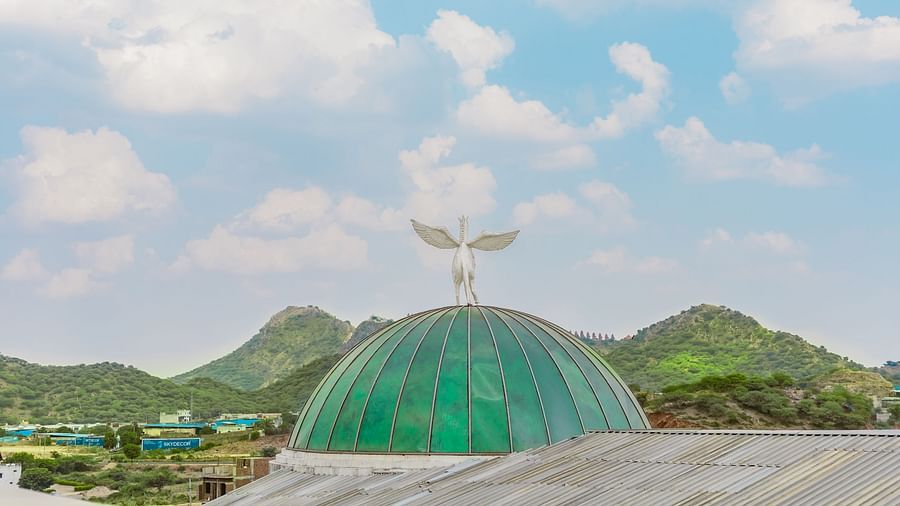 A dome shaped glass structure on top of a building with a view of the mountains and sky