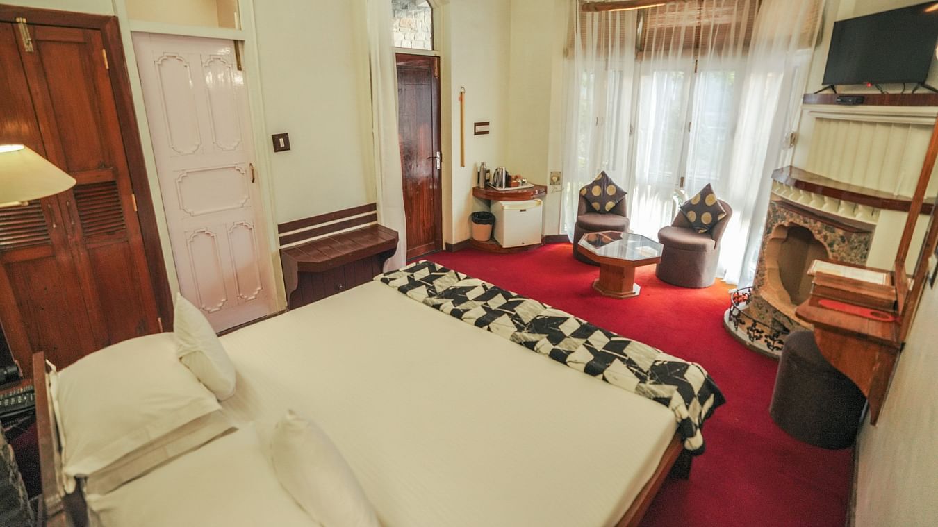 A bedroom with a bed, a rug, and warm lighting, interior setting - The Den Corbett Resort & Spa, Kumeria.