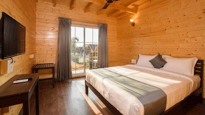 The interiors of the bedroom has wooden walls and a large curtain - White Wood Resort, Morjim