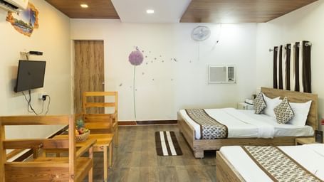 A wide view of a room with 2 beds, a TV, and light wood furniture, at Daksh Resort & Amusement Park, Sasan Gir.
