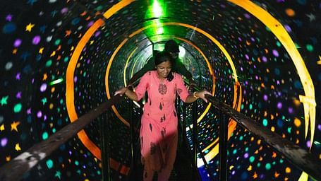 A Vortex room at MGM Dizzee World featuring people walking on a bridge and around it everything is rotating. It creates an illusion that the bridge is rotating.