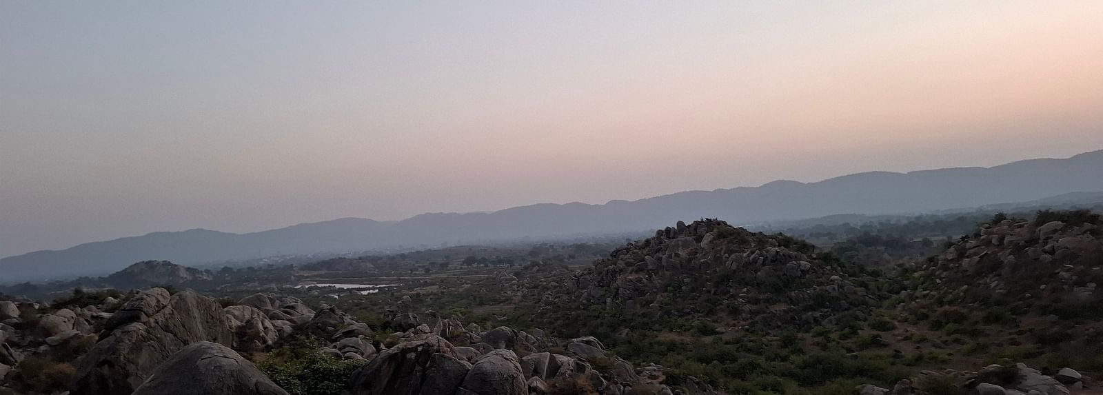Aerial view of a land with huge rocks and visuals of lake at a far away distance