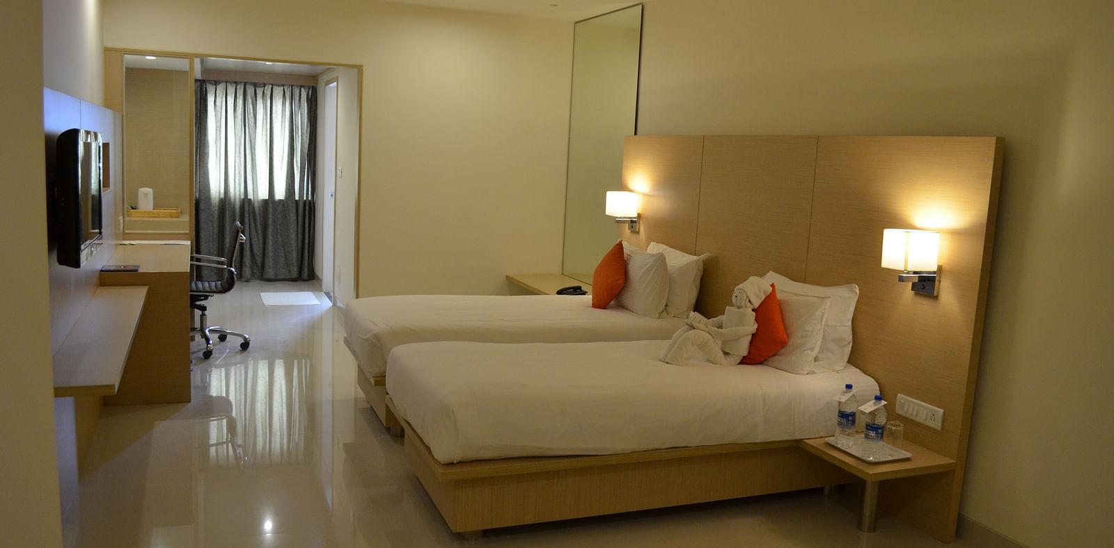 An image of twin beds with a television at a room at Regency Tiruttani by GRT Hotels. 