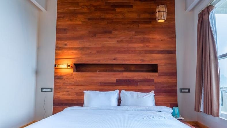 A narrow view of a bedroom with a bed, showcasing the warm wooden tones and minimalist design - Clarks Exotica Resort, Near Mukhteshwar.