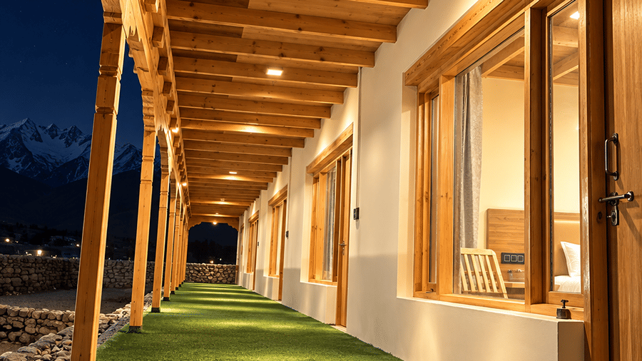 Covered outdoor corridor with wooden ceiling, glass windows and green flooring alongside the property.