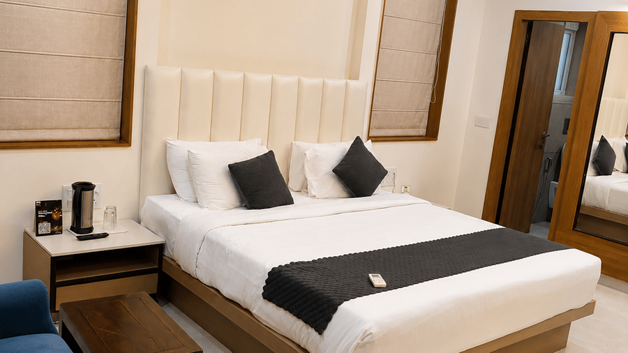 Suite at TGI Apple Inn, Ajmer Road, Jaipur featuring a bed, bedside tables, armchairs, blinds on the windows, and a door.
