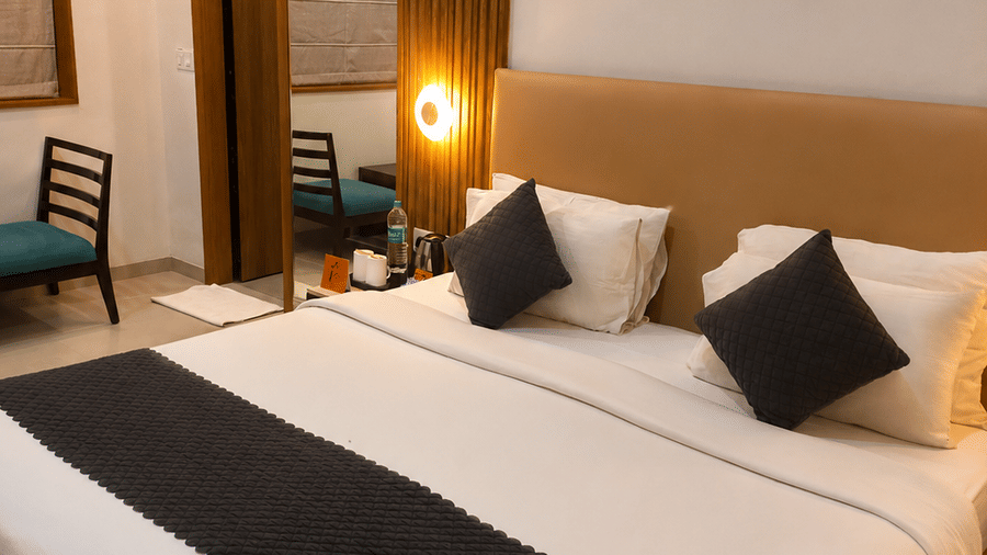Premium Room at TGI Apple Inn, Ajmer Road, Jaipur featuring a bed, pillows, lamps, artwork, mirror, and air conditioner.