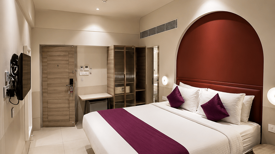 The Oriental Residency | A room with a large bed, spreads, pillows, and a television.