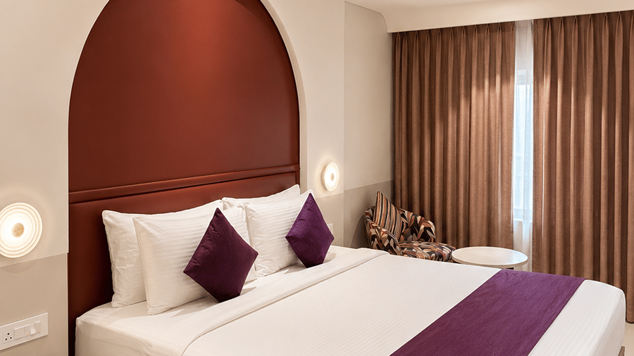 The Oriental Residency | A room with a large bed, spreads, pillows, and a television.