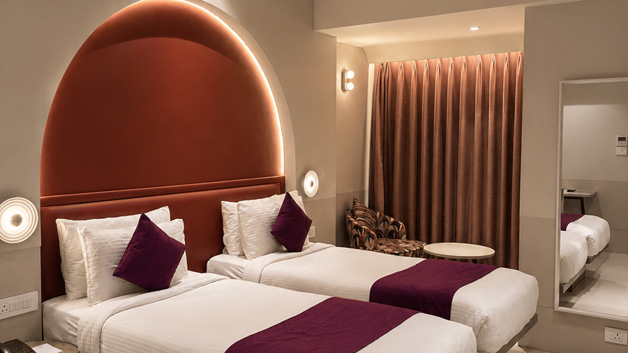 The Oriental Residency | A room with twin beds, spreads, pillows, and a television.