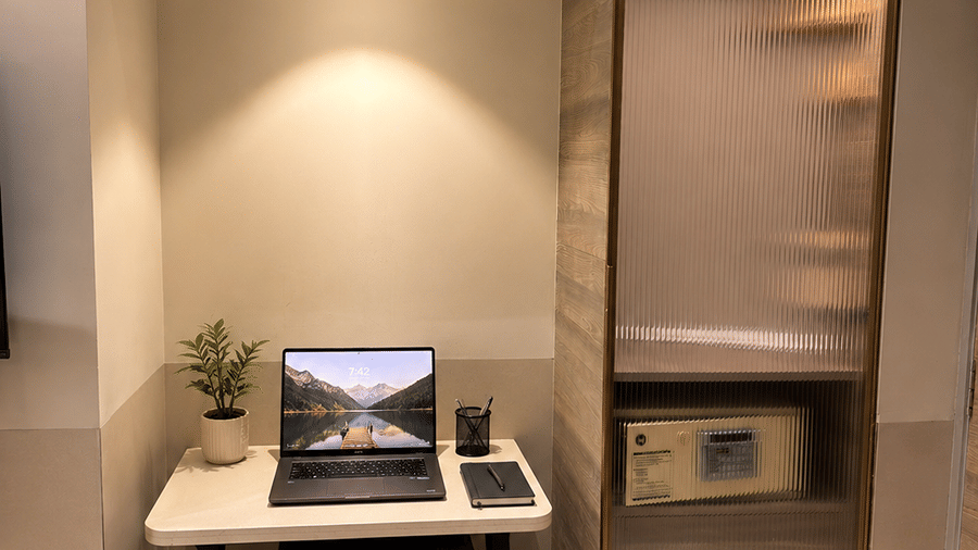 A office desk with a laptop, a table, and lights. | The Oriental Residency