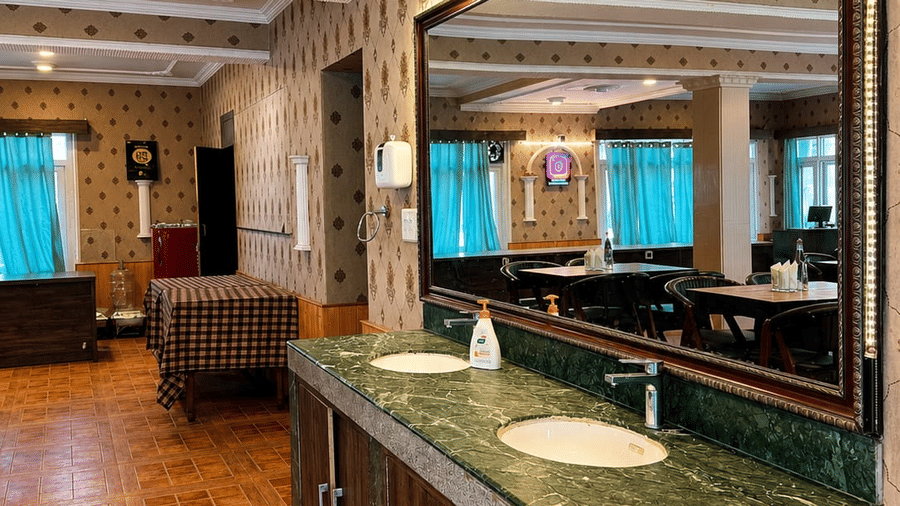A bathroom vanity area at Hotel Outlook, Pahalgam, featuring 2 sinks set into a counter beneath a large rectangular mirror on the wall.