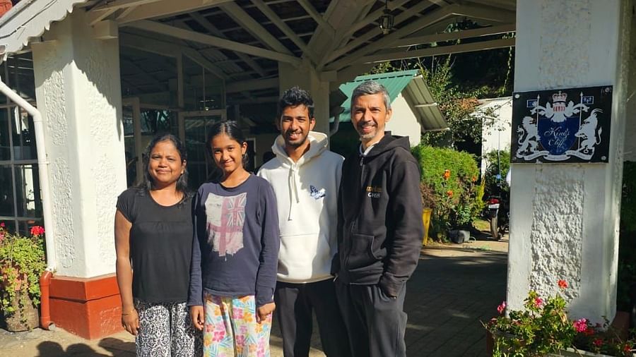 Group of guests posing at the entrance of a white cottage-style resort building.