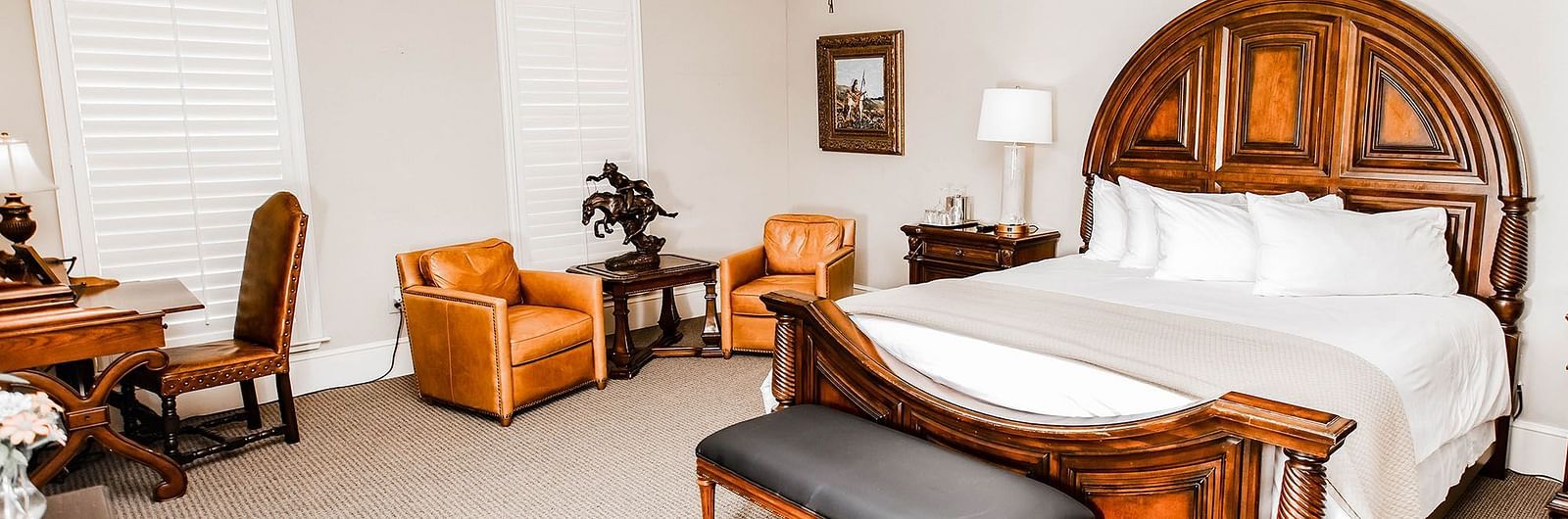 A traditional bedroom featuring a wooden bed, elegant decor, and a ceiling fan, providing a comfortable and timeless space - The Grand Hotel & Ballroom, McKinney