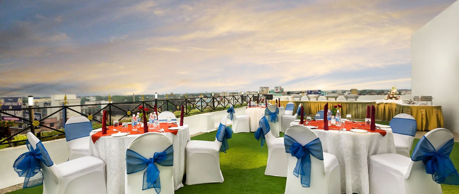 A banquet hall with white chairs laced with blue ribbons pointing towards the stage at Regency Kanchipuram by GRT Hotels.