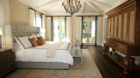 Side view image of the bed with a chandelier hanging over the double bed.