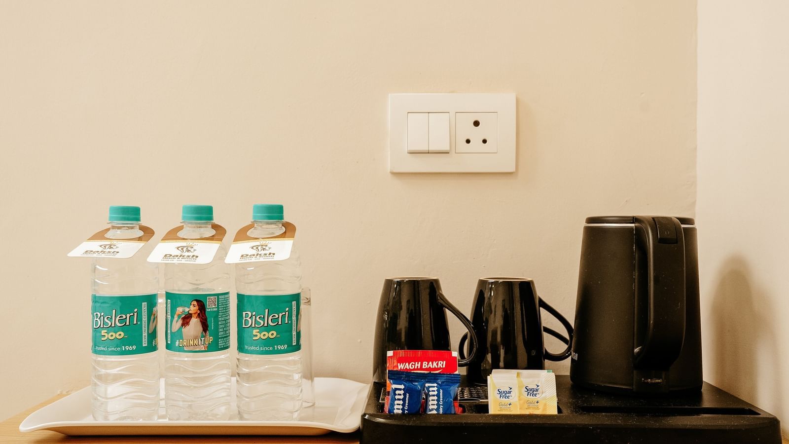 Refreshment station at the Pride Room at Daksh The Grand Gowardhan, Dwarka, with bottled water and a kettle.
